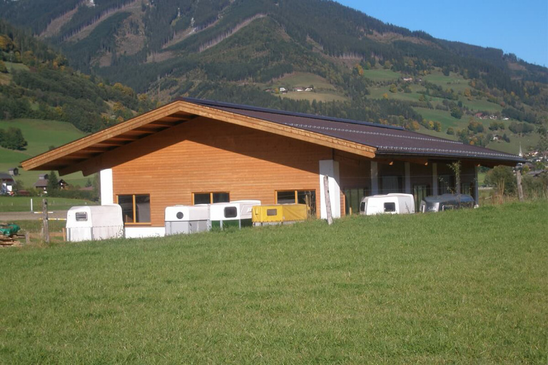 Moderne Holzkonstruktion im Pinzgau, umgeben von Wiesen und Bergen, für nachhaltiges Bauen.