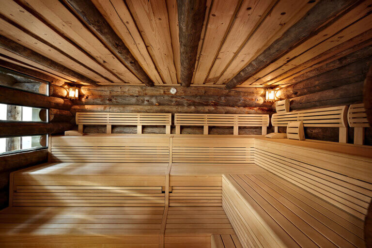 Holzsauna aus hellem Holz mit Bänken, gemütlich gestaltet für Entspannung und Wellness.