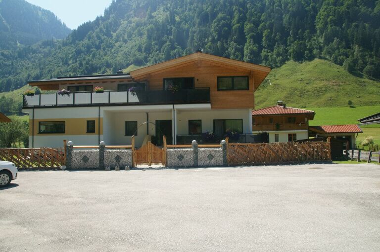 Moderne Holzarchitektur in Piesendorf umgeben von Alpenlandschaft und Parkplätzen.