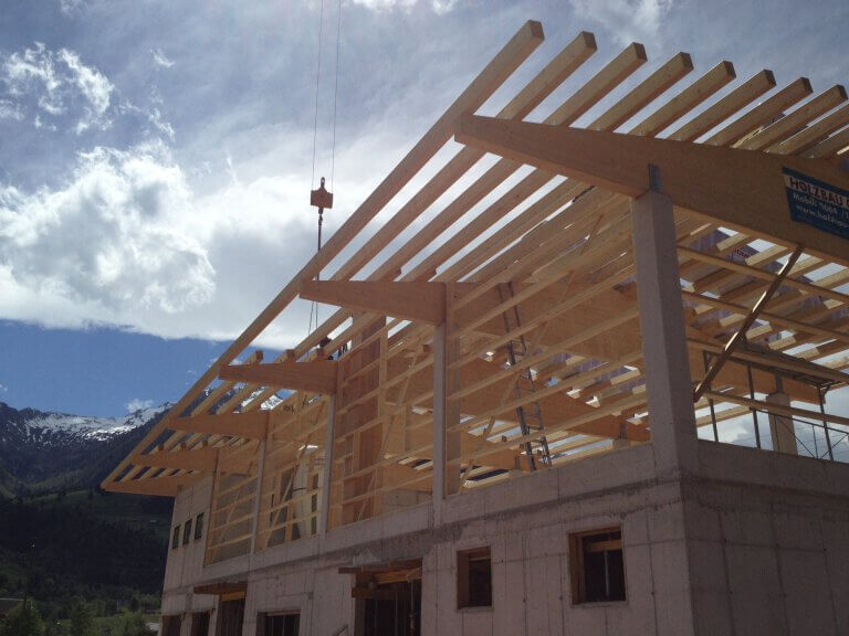 Holzbauprojekt mit Dachkonstruktion unter blauem Himmel in Piesendorf, Pinzgau.