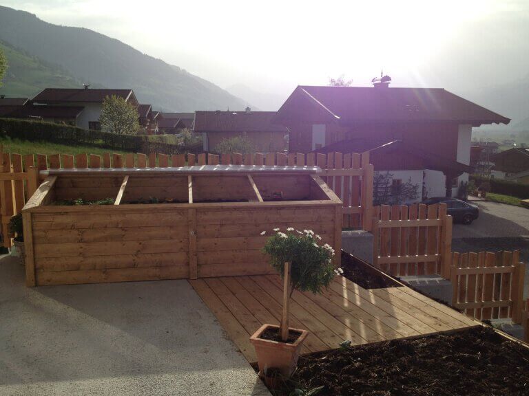 Holzkonstruktion mit Hochbeet und Terrasse in naturnahem Garten in Piesendorf.