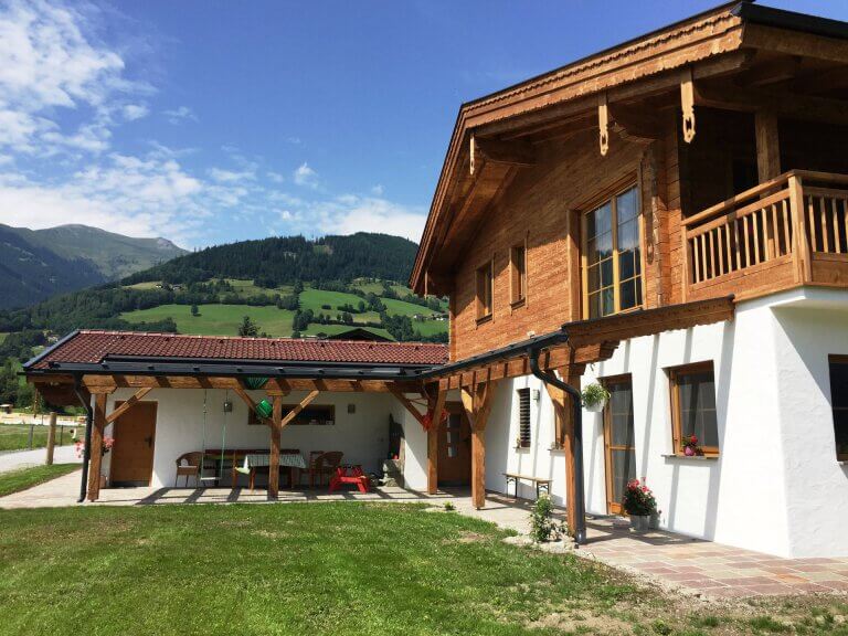 Holzhaus mit Garten in Piesendorf, umgeben von grüner Landschaft und Bergen.