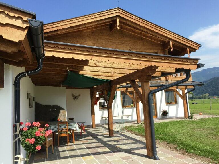 Moderne Holzbau-Architektur mit Terrasse und Blumen im Pinzgau, ideal für Garten- und Wohnprojekte.