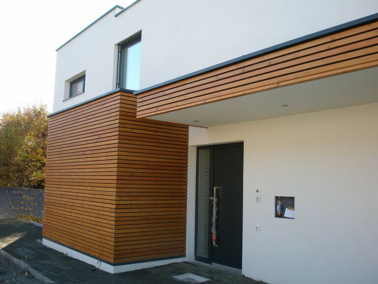Moderner Holzbau mit fassadenverkleidung aus Holzleisten und großem Eingang in Piesendorf.