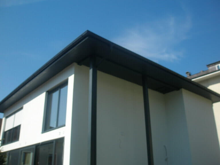 Moderner Holzbau mit großen Fenstern und Dachüberstand, ideal für nachhaltigen Wohnraum.