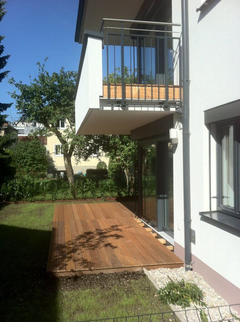 Gartenbereich mit Holzterrasse und Balkon in modernem Wohnhaus in Piesendorf.