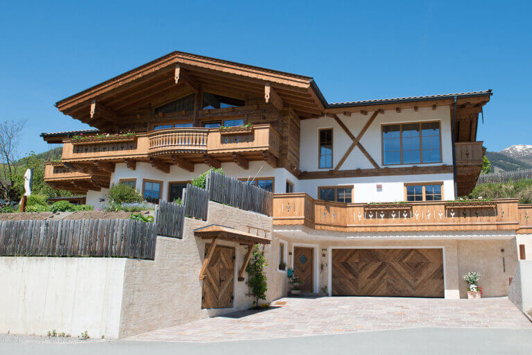 Ein modernes Holzhaus mit Balkon und Garagenfront in malerischer Umgebung.